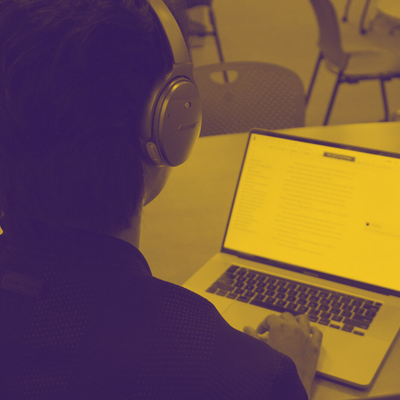 Tutor wearing headphones working in front of laptop